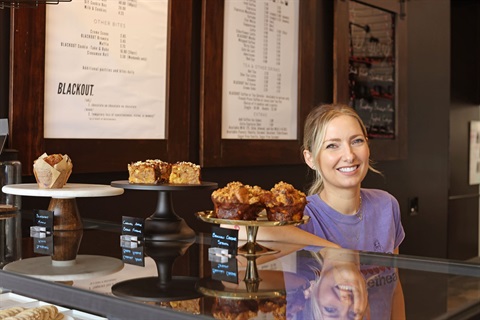 Female bakery owner poses in her shop