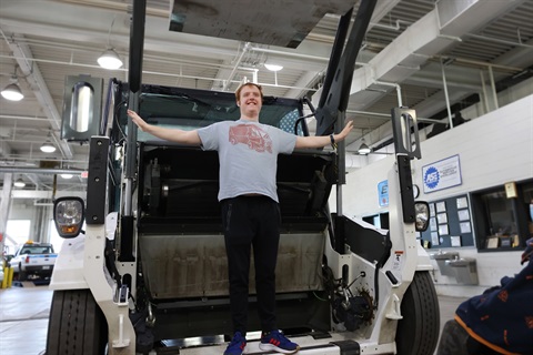 Person smiling and posing on a Public Works vehicle.