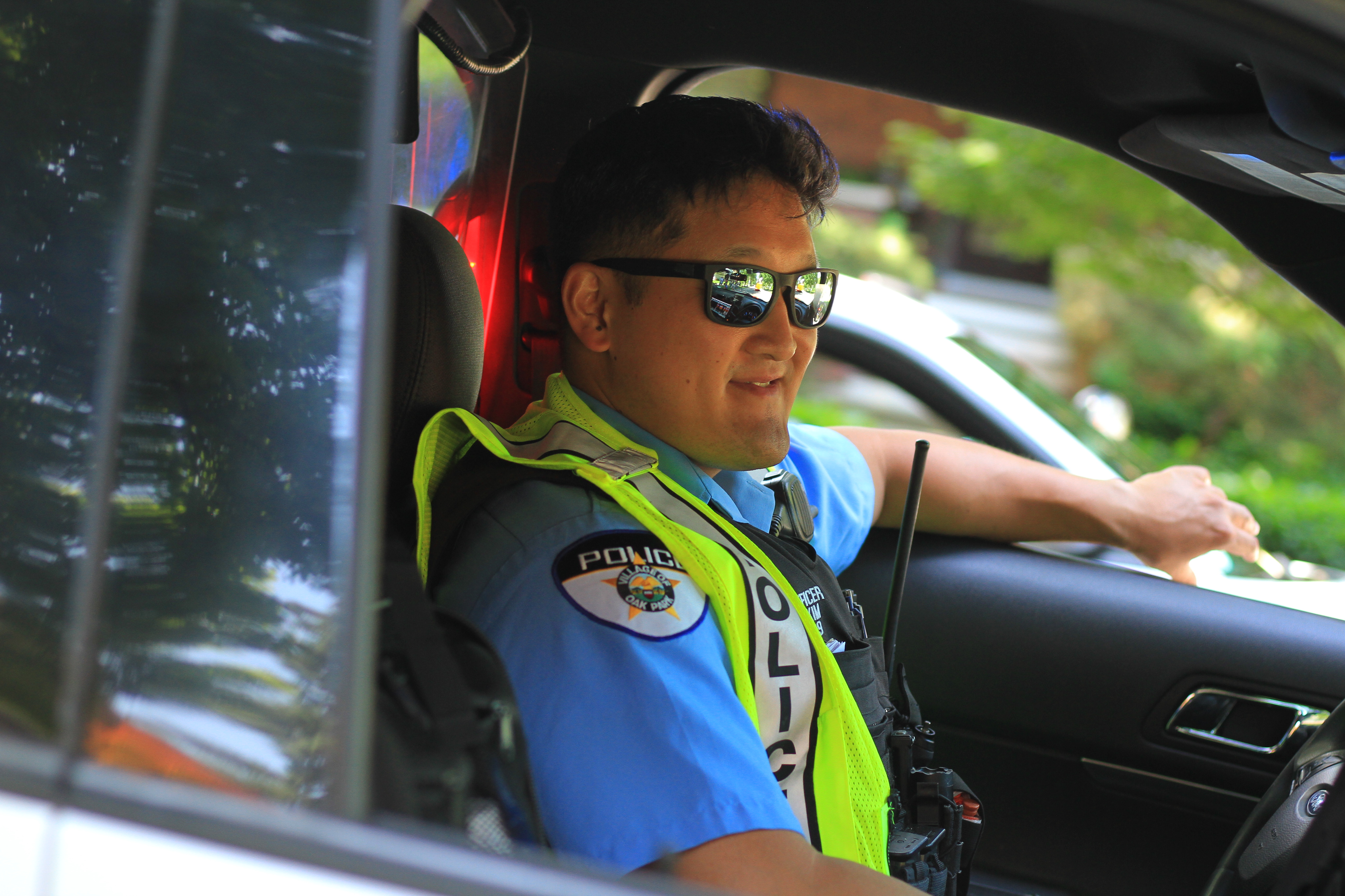 Police officer wearing sunglasses and neon vest sitting in vehicle